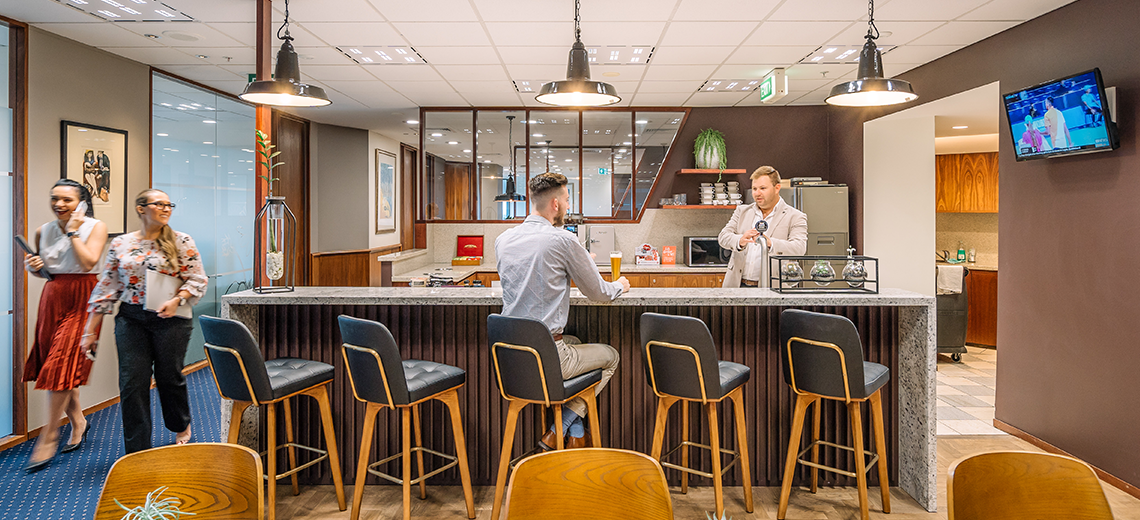 Clients enjoying coffee and networking in a fully stocked kitchen.