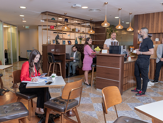 Clients networking over coffee and working in hot desk and booth areas at Doha Tower coworking space.